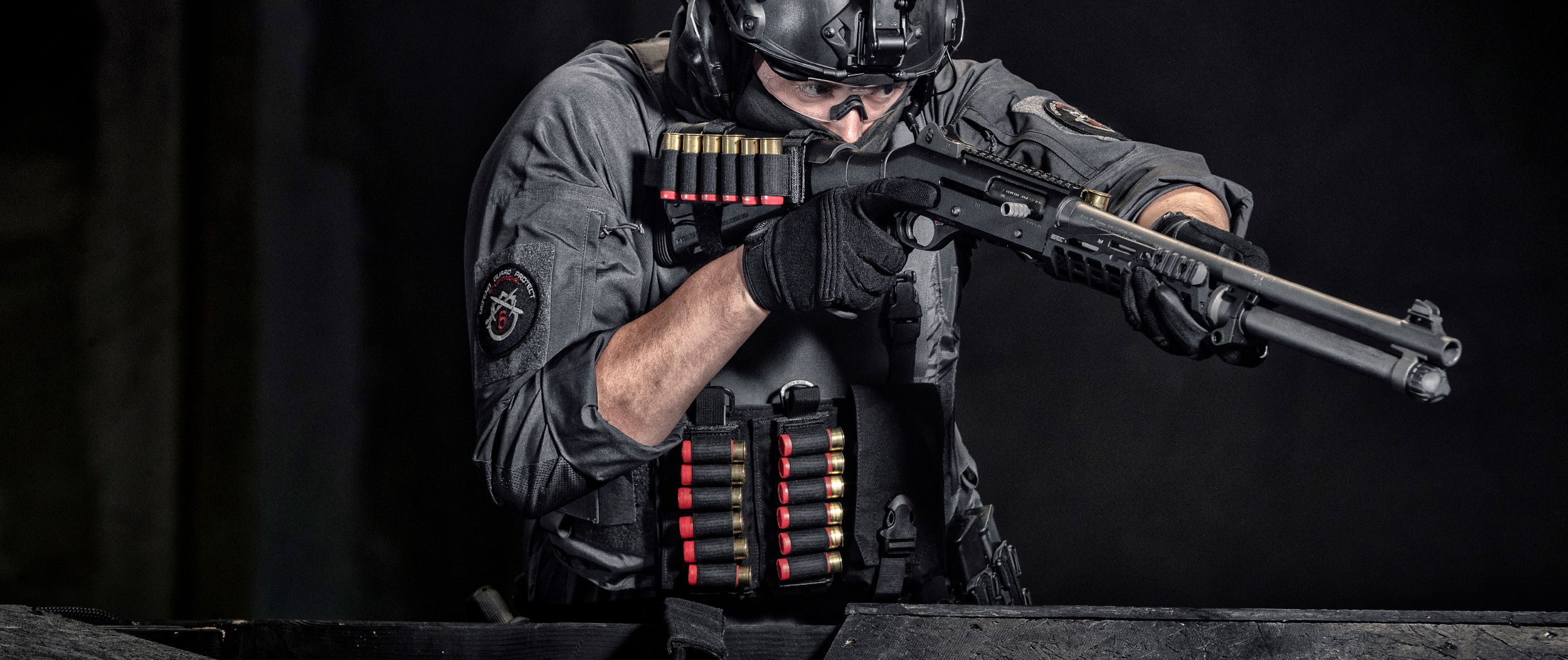 Image of a guy pointing a shotgun that has the buttstock shotgun shell platform.
