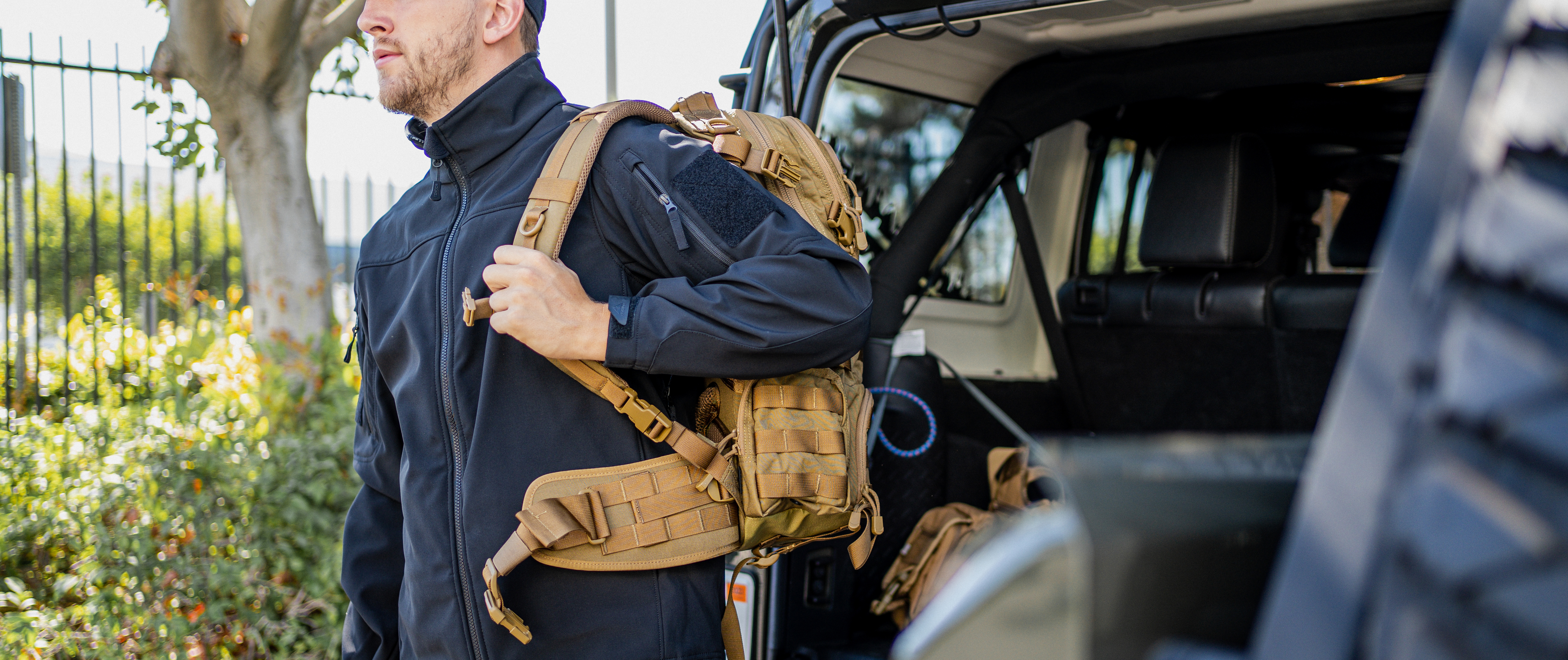 Image of a guy holding a backpack while in the westpac softshell jacket