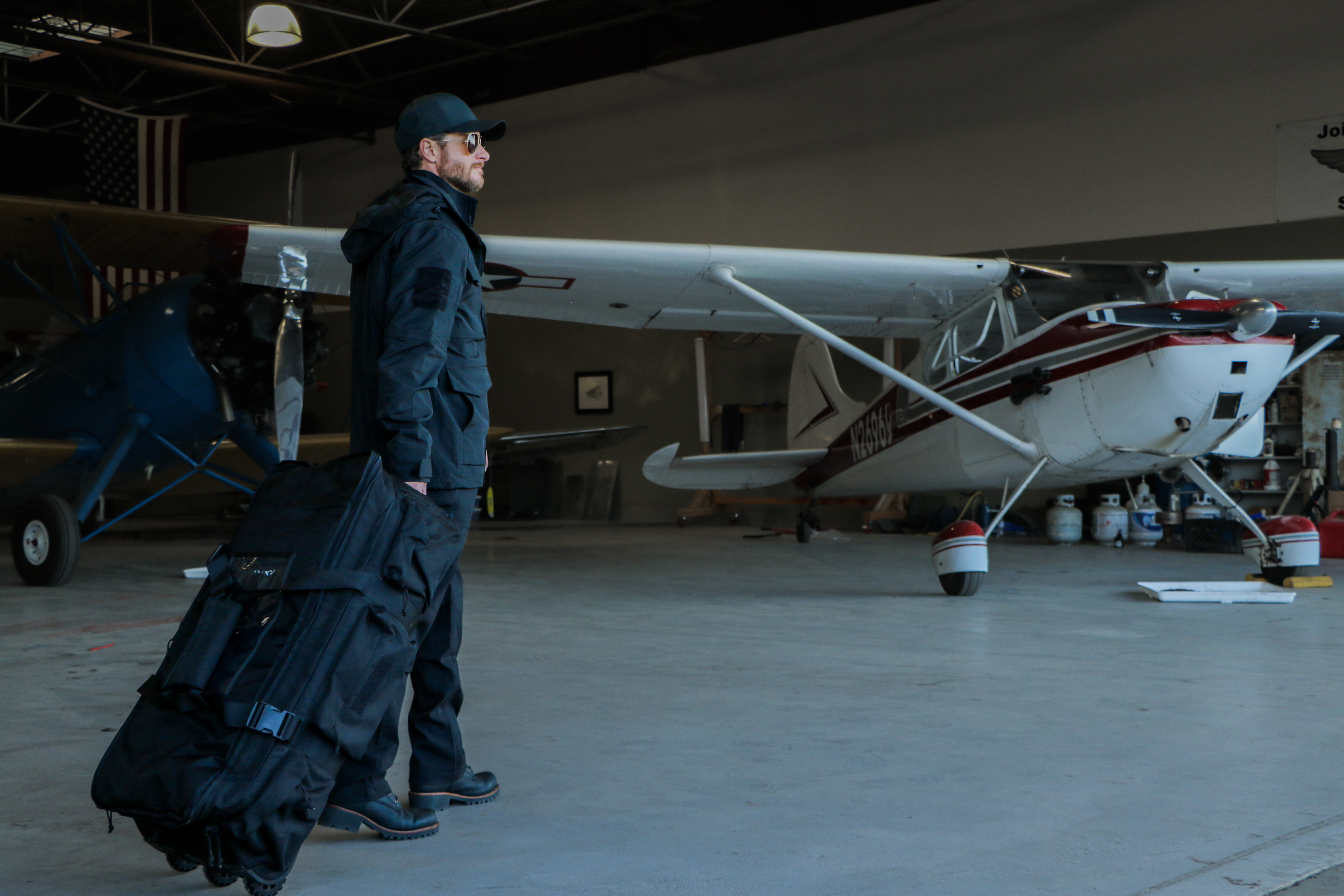 image of a person next to a plane wearing the waterproof parka with the hood up