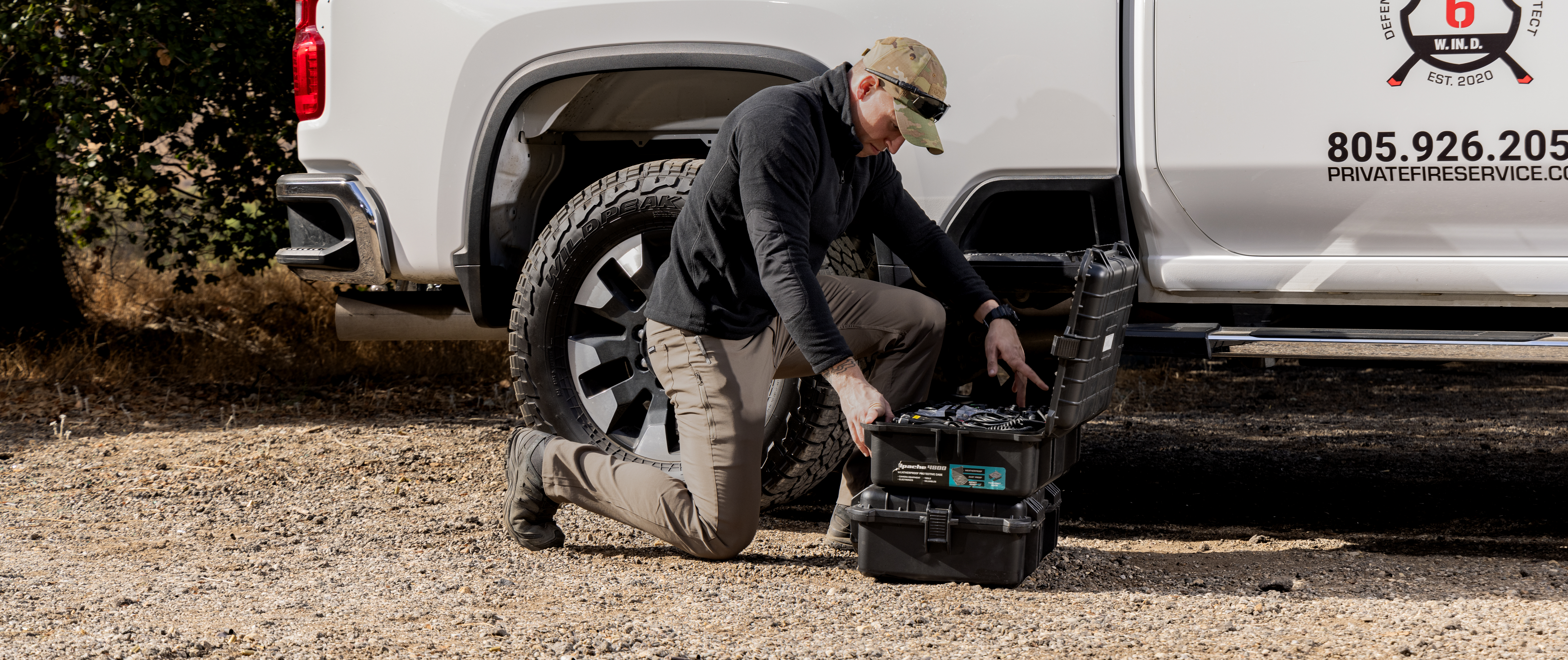 Man kneeling next to a tough box full of gear and looking through it.