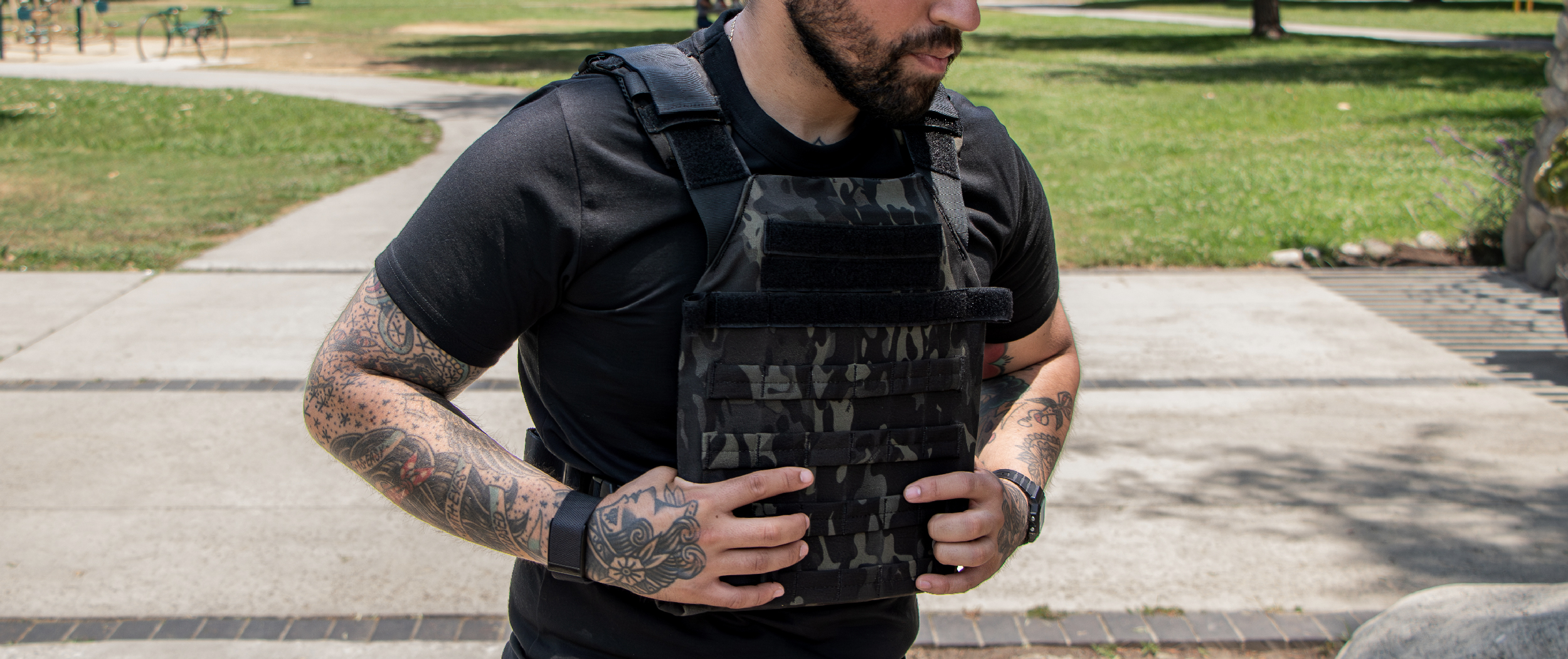 Image of someone taking off their multicam black plate carrier at the park