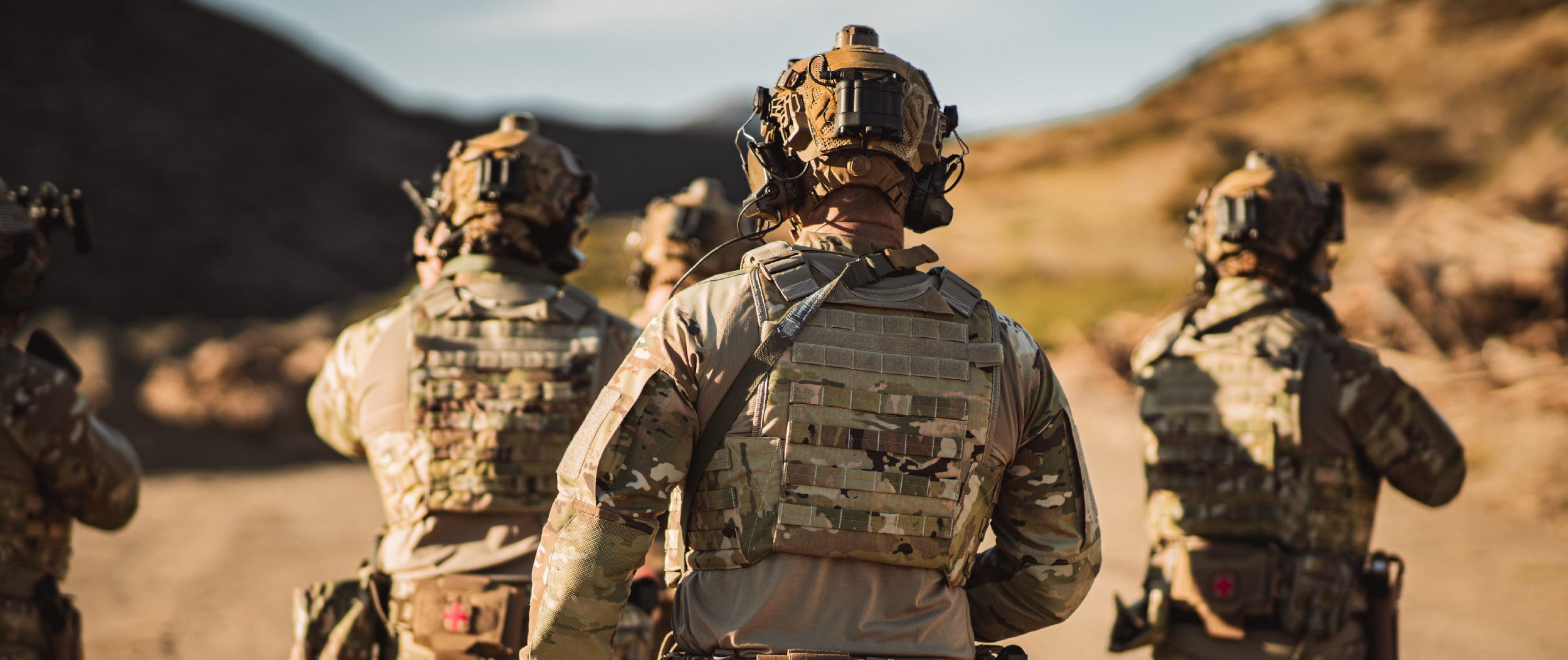 Image of a few soldiers walking away in full tactical gear while wearing mopc